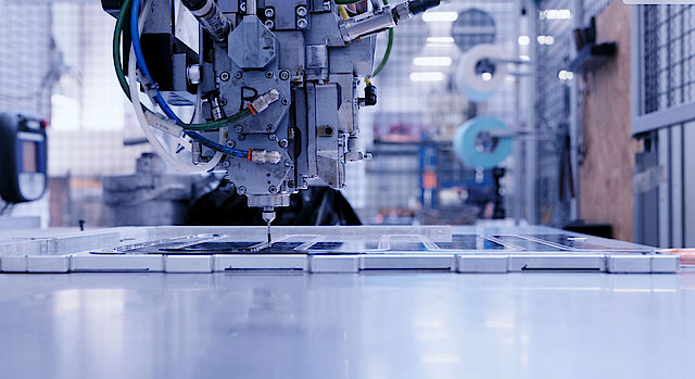 CNC-Maschine bei der Fertigung von mechanischen Bauteilen: Fräswerkzeug bearbeitet Metallplatten in einer Industrieumgebung, Kabel und Pneumatikleitungen sichtbar, Fokus auf Präzisionsbearbeitung.